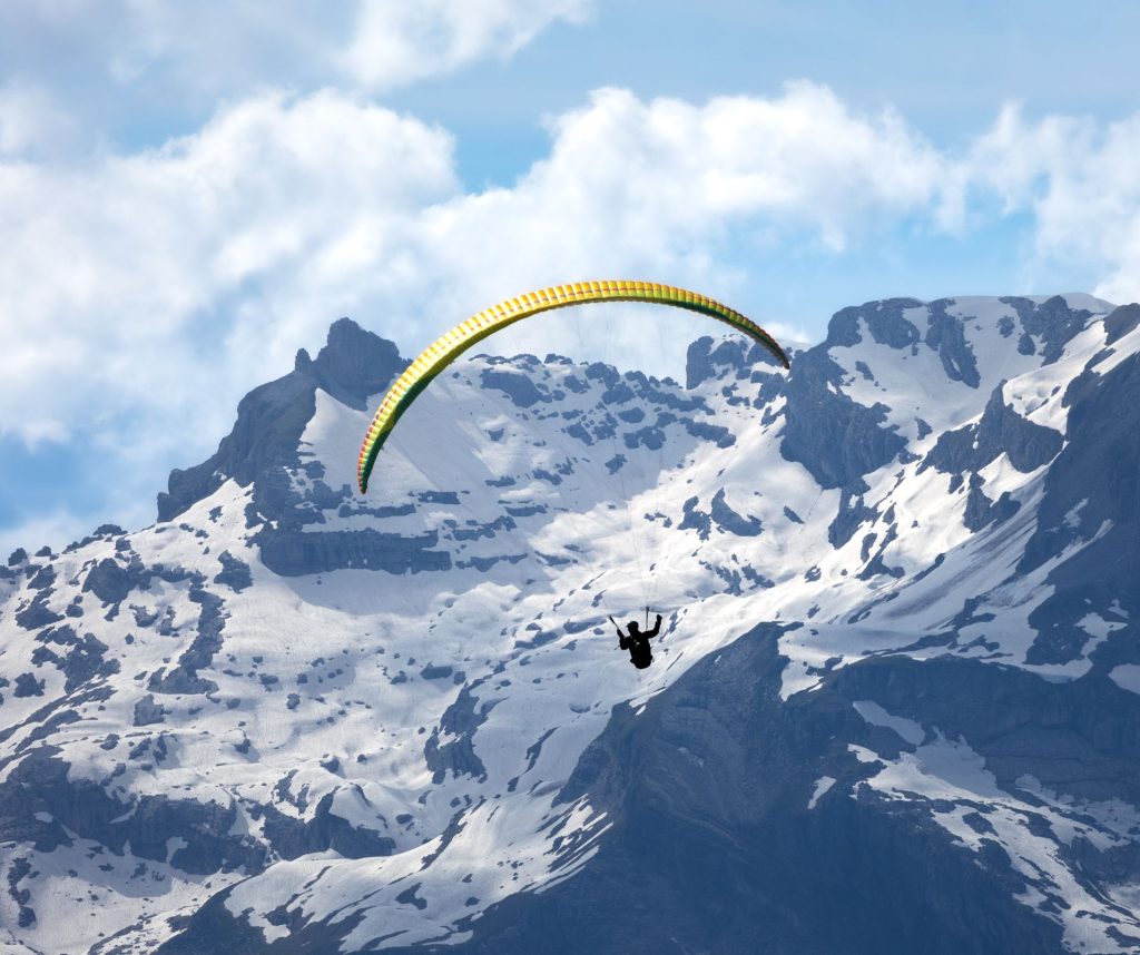 Parapentiste en vol face à une chaîne de montagnes