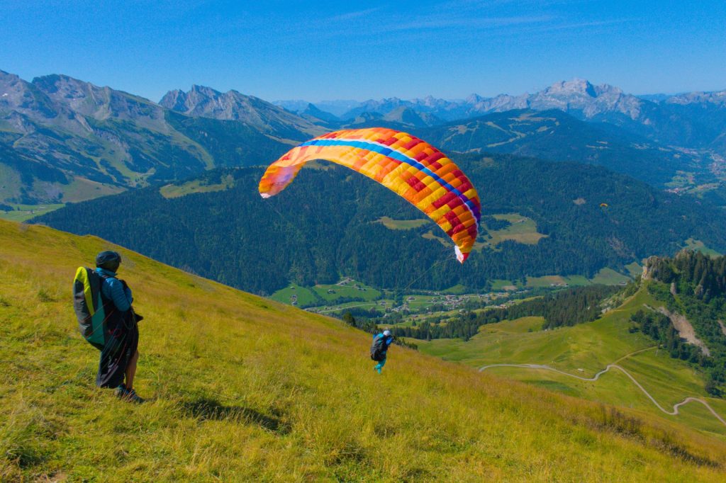 Décollage parapente devant des sommets enneigés en haute montagne